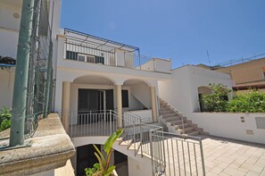Un edificio residencial de varios niveles con escaleras, balcones y una entrada protegida por un portón.