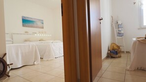 Una habitación con una cama, una mesita, una silla y una puerta de madera.