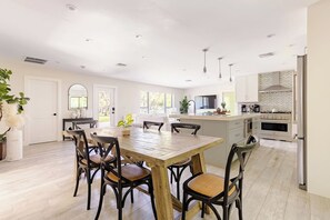 A modern kitchen with a central island, built-in appliances, and a dining area with a wooden table and chairs. - Stylish 3BR w/ Heated Pool · 7 Mins to Beach (Jupiter)