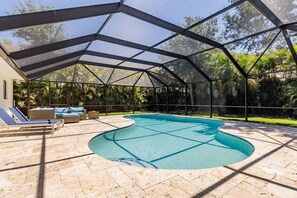 Une piscine extérieure couverte, dotée de chaises longues et d’un espace patio.