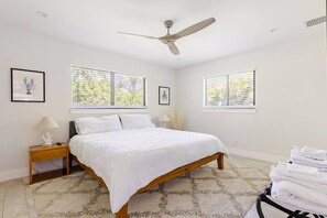 A bedroom with a bed, two bedside tables, a ceiling fan, and windows with blinds. - Stylish 3BR w/ Heated Pool · 7 Mins to Beach (Jupiter)