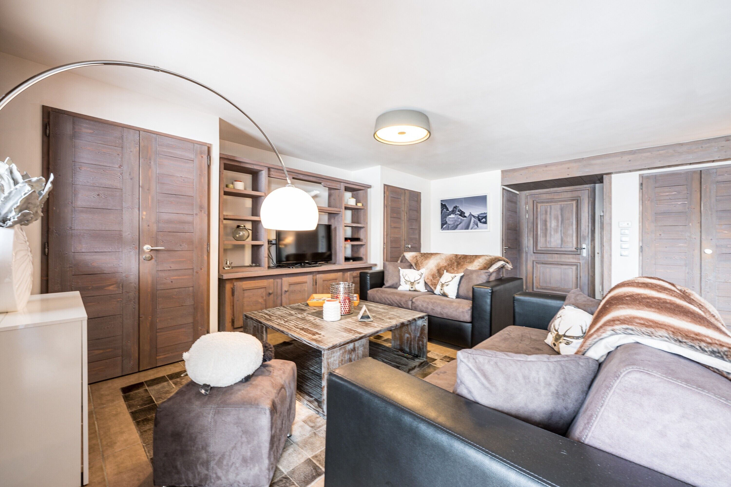 Ein Wohnzimmer mit einer Couch, einem Sessel, einem Couchtisch und einem Fernseher.