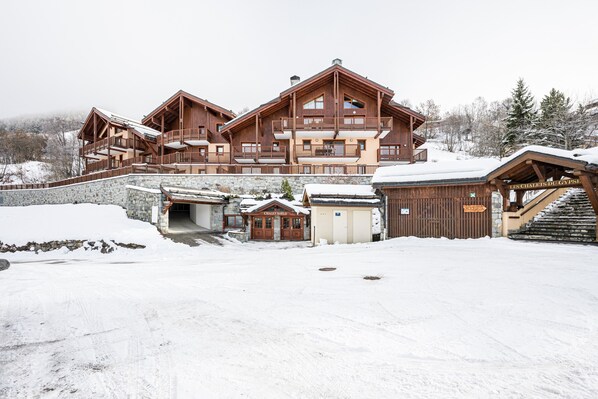 A large wooden chalet with multiple balconies, a stone entrance, and a sign reading 'Les Chalets du Gypsey.'