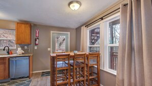 Una cocina con armarios de madera, lavavajillas integrado, una ventana con cortinas y un extintor en la pared.