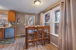 Eine Küche mit Holzausstattung, einem eingebauten Geschirrspüler, einem Fenster mit Vorhängen und einem an der Wand befestigten Feuerlöscher.