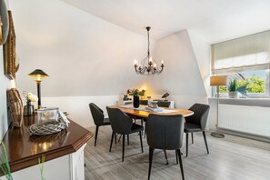 Ein moderner Essbereich mit Holztisch, schwarzen Stühlen, einer Pendelleuchte und Blick auf Grün durch ein Fenster.