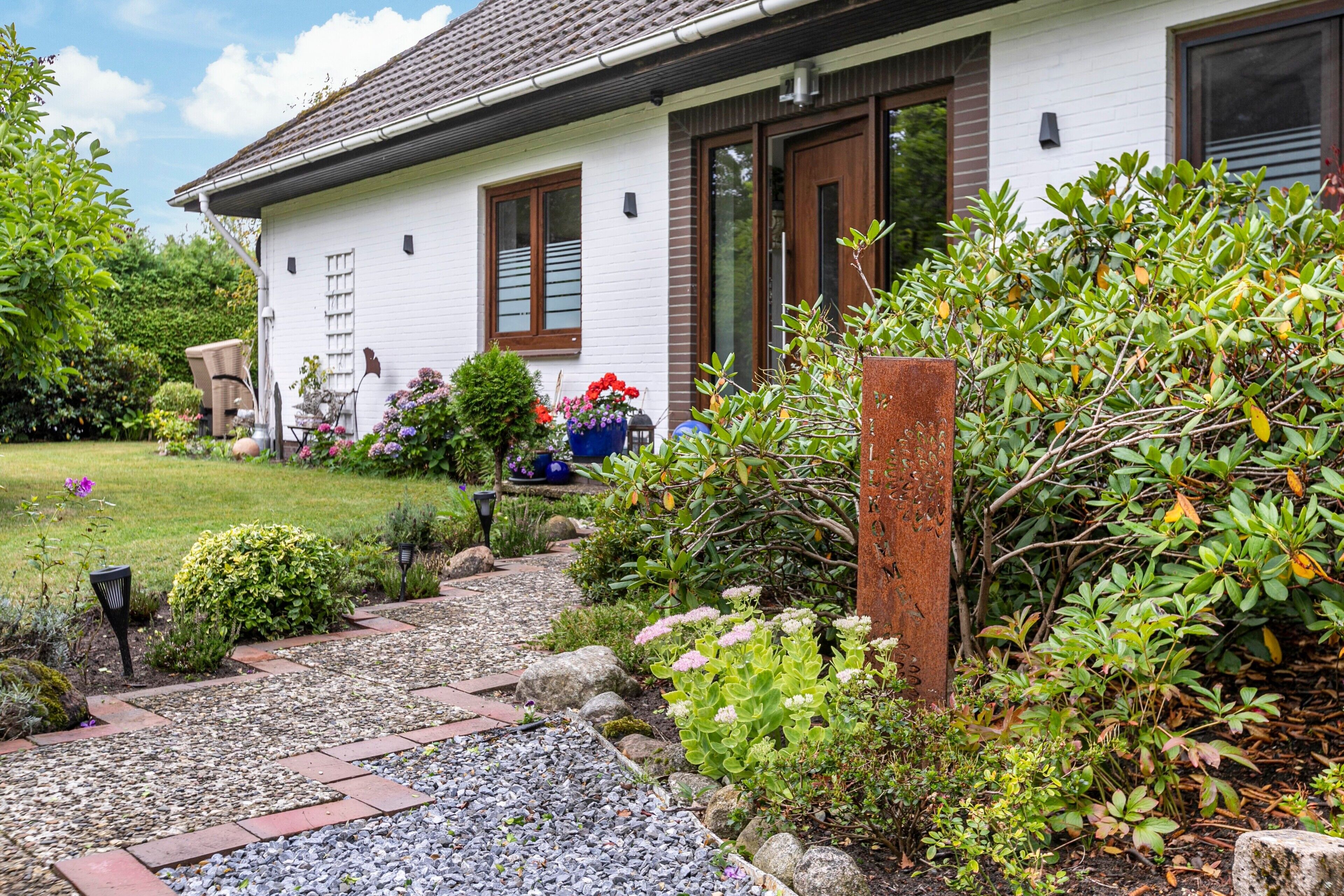 Et hvidt hus med en havegang, der fører til indgangen.