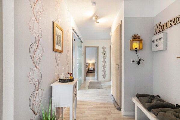 A hallway with a white console table, a framed picture, and a wall-mounted light fixture.