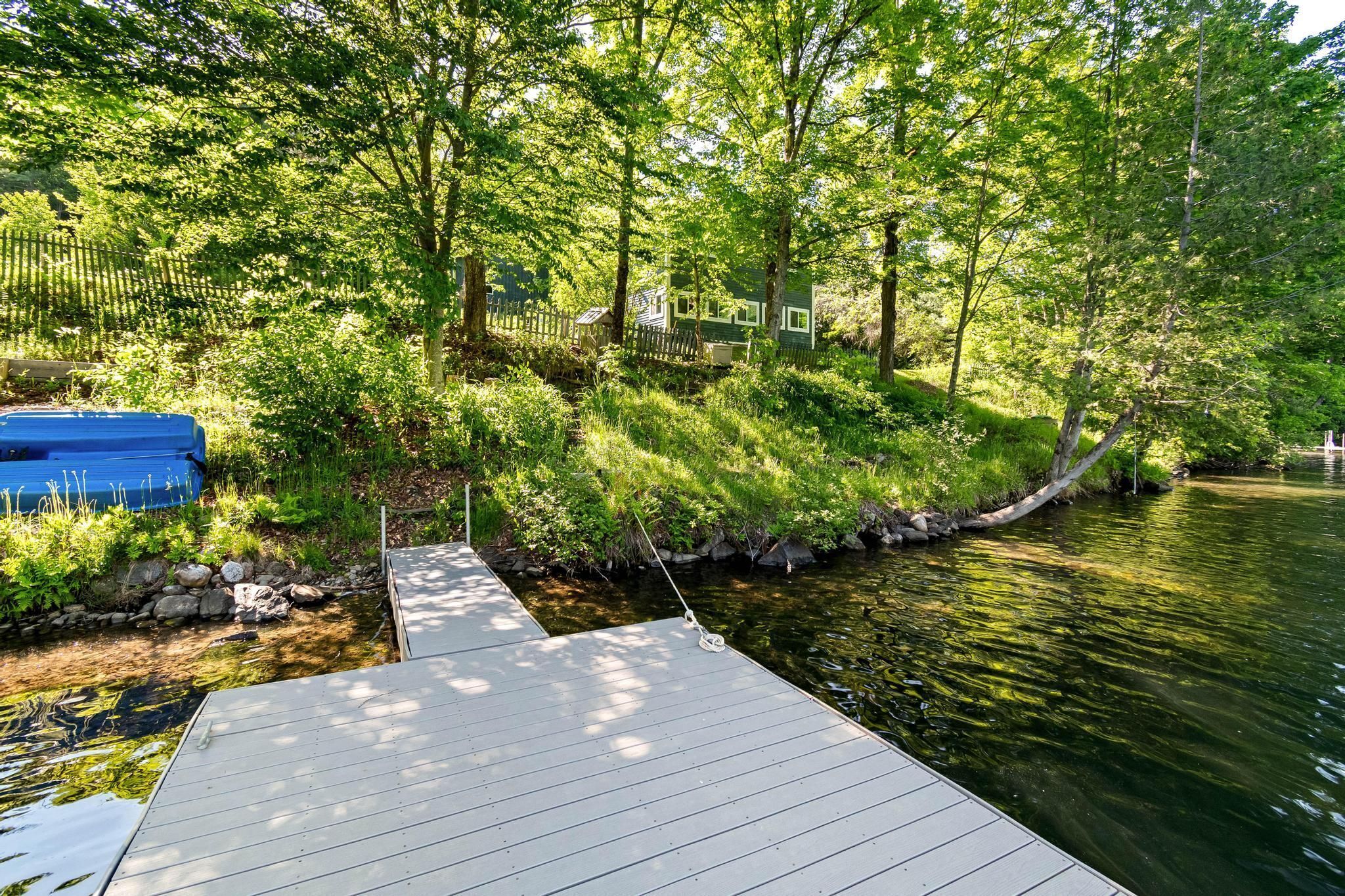 A wooden dock extending into a calm river, surrounded by lush greenery and trees.