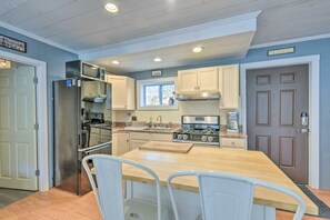 A compact kitchen with a central island, stainless steel appliances, and white cabinetry.