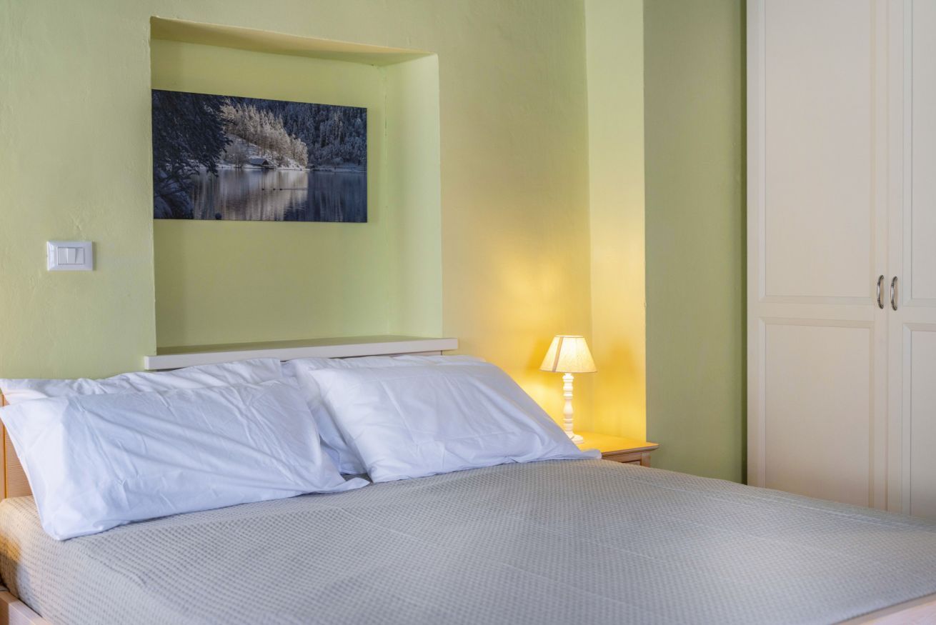 Ein Schlafzimmer mit einem Bett, einem Nachttisch mit Lampe, einem Bild an der Wand und einem Kleiderschrank.