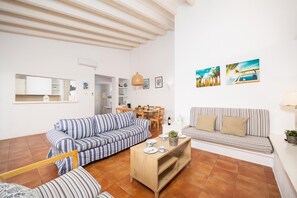 A living room with a striped sofa, a wooden coffee table, and a dining area with a table and chairs.