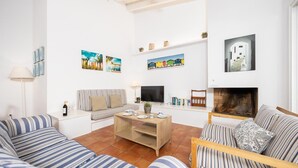 A living room with striped sofas, a coffee table, a TV, books, and artwork on the walls.