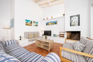 A living room with striped sofas, a coffee table, a TV, books, and artwork on the walls.