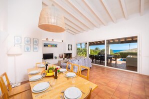 A dining area with a wooden table set for four, a television, and a fireplace.
