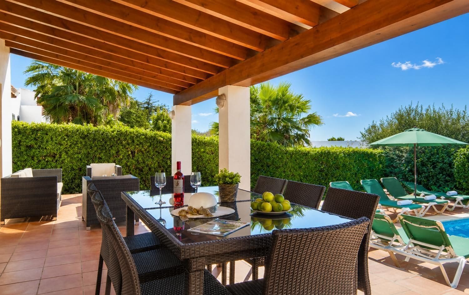 Un patio al aire libre con una mesa, sillas, una piscina y sillones de descanso.