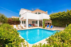 A modern villa with a swimming pool, outdoor seating, and lush greenery. - Villa Sa Calma - Four Bedroom Villa, Sleeps 8 (Puerto Luz)