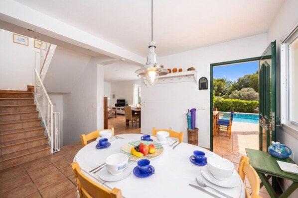A dining area with a round table, chairs, and a fruit basket. - Villa Sa Calma - Four Bedroom Villa, Sleeps 8 (Puerto Luz)