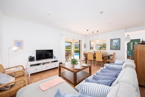 A living room with a TV, sofa, dining table, and chairs. - Villa Sa Calma - Four Bedroom Villa, Sleeps 8 (Puerto Luz)