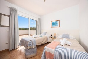 A hotel room with two beds, a large window, a painting, and a view of the outdoors. - Villa Sa Calma - Four Bedroom Villa, Sleeps 8 (Puerto Luz)