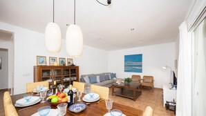 Comedor con mesa de madera dispuesta para seis personas, rodeado de sillas de mimbre.