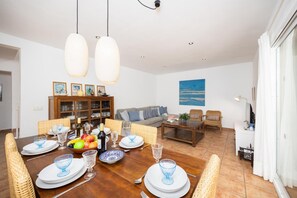 Een eetruimte met een houten tafel voor zes personen, omringd door rieten stoelen.