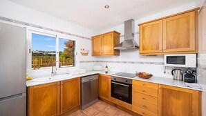 Una cocina moderna con armarios de madera, lavavajillas, horno, microondas y ventana con vistas al exterior.