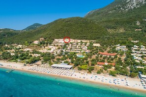 An aerial view of a coastal town with a beach, villas, and a mountain backdrop. - Villa Aurora - Three Bedroom Villa, Sleeps 6 (Mparmpati)