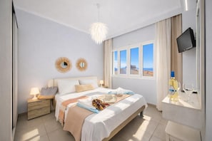 Una camera da letto con un letto, comodini, una TV, una finestra con vista e una bottiglia di alcolici.
