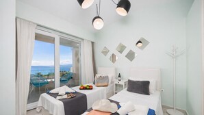 Une chambre d’hôtel avec deux lits, un balcon offrant une vue agréable et un coin repas avec une table et des chaises.
