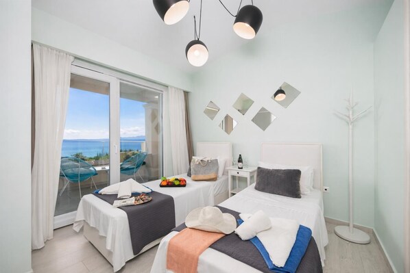 Une chambre d’hôtel avec deux lits, un balcon offrant une vue agréable et un coin repas avec une table et des chaises.