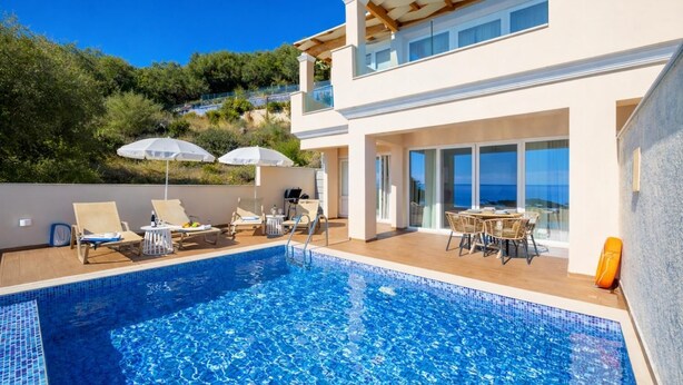 Un espace moderne aménagé au bord de la piscine, avec des chaises longues, des parasols et une vue dégagée sur la mer.