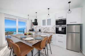 A modern kitchen with a marble countertop, stainless steel appliances, and a view of the ocean. - Villa Leo - Two Bedroom Villa, Sleeps 4 (Mparmpati)
