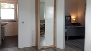 A room with a large mirror, a bed, a bedside table with a lamp, and a window. - Apartment "Olsberg View Whg. B" with Mountain View, Shared Garden and Wi-Fi (Olsberg)