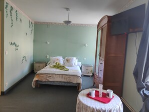 Ein Schlafzimmer mit Bett, Nachttischen, einem Kleiderschrank, einem Tisch mit Tassen und Wanddekorationen.