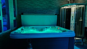 A hot tub in a room with a tiled wall and a glass enclosure. - Room “Domaine du Chêne” (La Vôge-les-Bains)