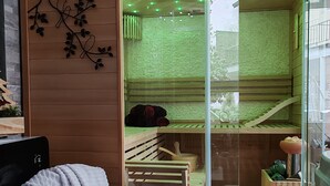 A room with a sliding glass door leading to a sauna area, a wooden bench, and a small wooden cabinet. - Room “Domaine du Chêne” (La Vôge-les-Bains)