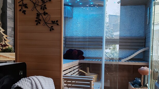 Una habitación moderna con separador de vidrio, mobiliario de madera e iluminación azul en el techo.