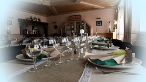 Un comedor con mesas dispuestas para una comida, una estantería para vinos y un cartel que dice 'La Poste' al fondo.