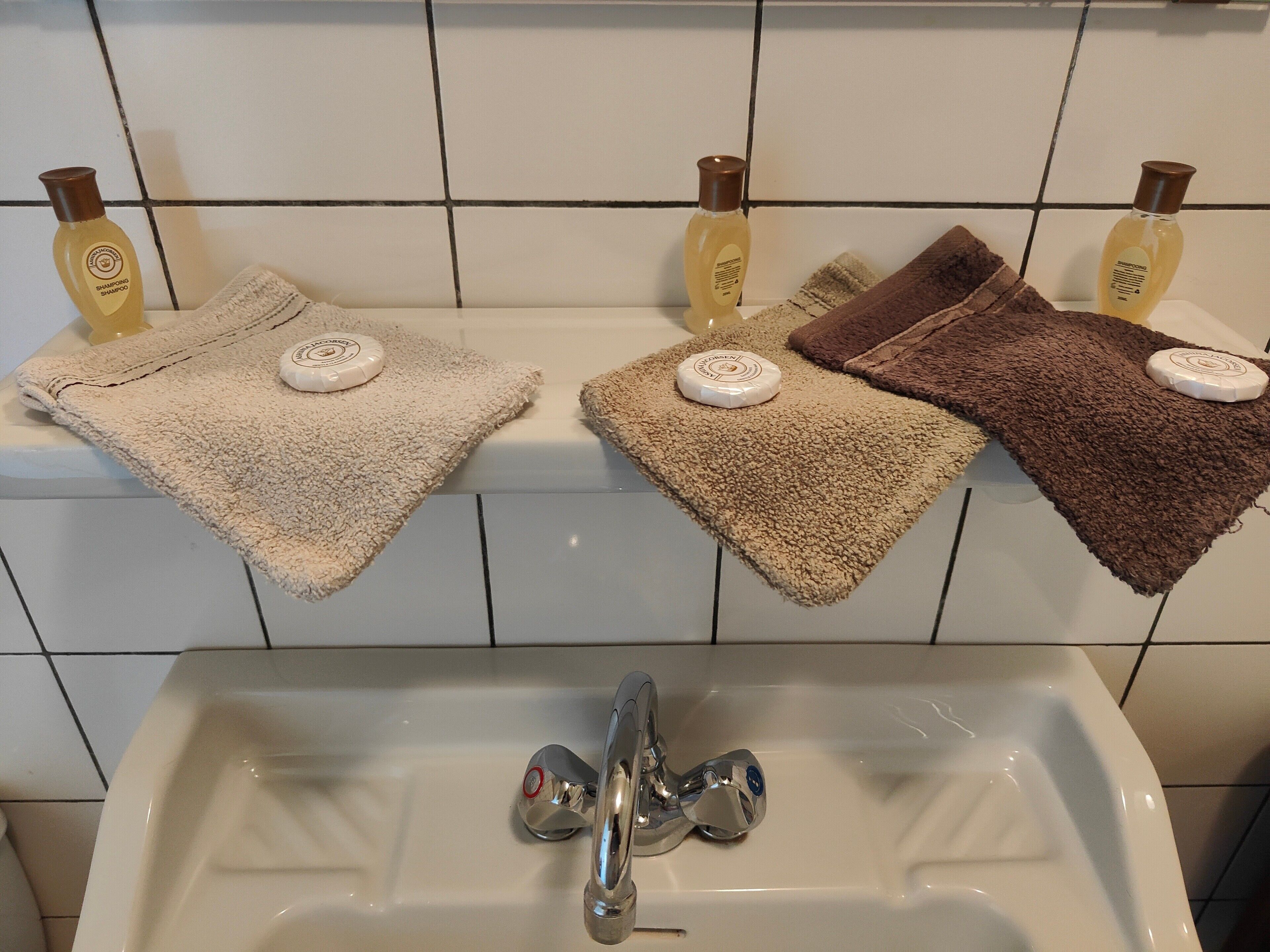 Un baño con un lavabo, dos toallas y dos botellas de champú.
