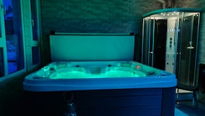 Ein Whirlpool in einem Raum mit gefliesten Wänden und einer Glaseinfassung.