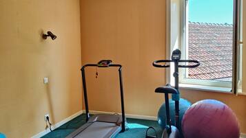 Een kamer met een loopband, een trainingsbal en een raam met uitzicht op een gebouw.
