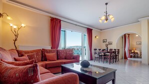 Een woonkamer met een zithoek, een salontafel, en een eethoek met stoelen en een tafel.