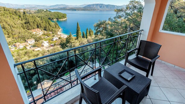 Een balkon met rieten meubilair met uitzicht op een meer en bergen.