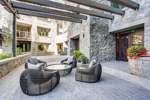 A stone-clad outdoor seating area with wicker furniture and potted plants. - Luxury 3BR in Vail w/ Balcony, Pool Access & More! (Vail)