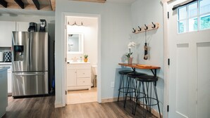 A modern kitchen with a stainless steel refrigerator, wooden flooring, and a bar area with stools. - Cozy Carriage House near Clemson - full kitchen, deck, fire pit, grill, and more (Central)