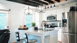 A modern kitchen with a central island, stainless steel appliances, pendant lighting, and a view to the outside. - Cozy Carriage House near Clemson - full kitchen, deck, fire pit, grill, and more (Central)