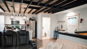 Eine moderne Küche mit Edelstahlgeräten, ein Essbereich mit Bar und ein Wohnzimmer mit Ledersofas.