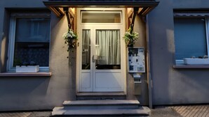 A hotel entrance with a double door, a small porch, and two flower baskets.