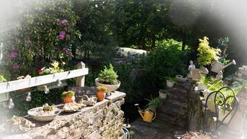 Un giardino con piante in vaso, un muro in pietra e una recinzione in legno.
